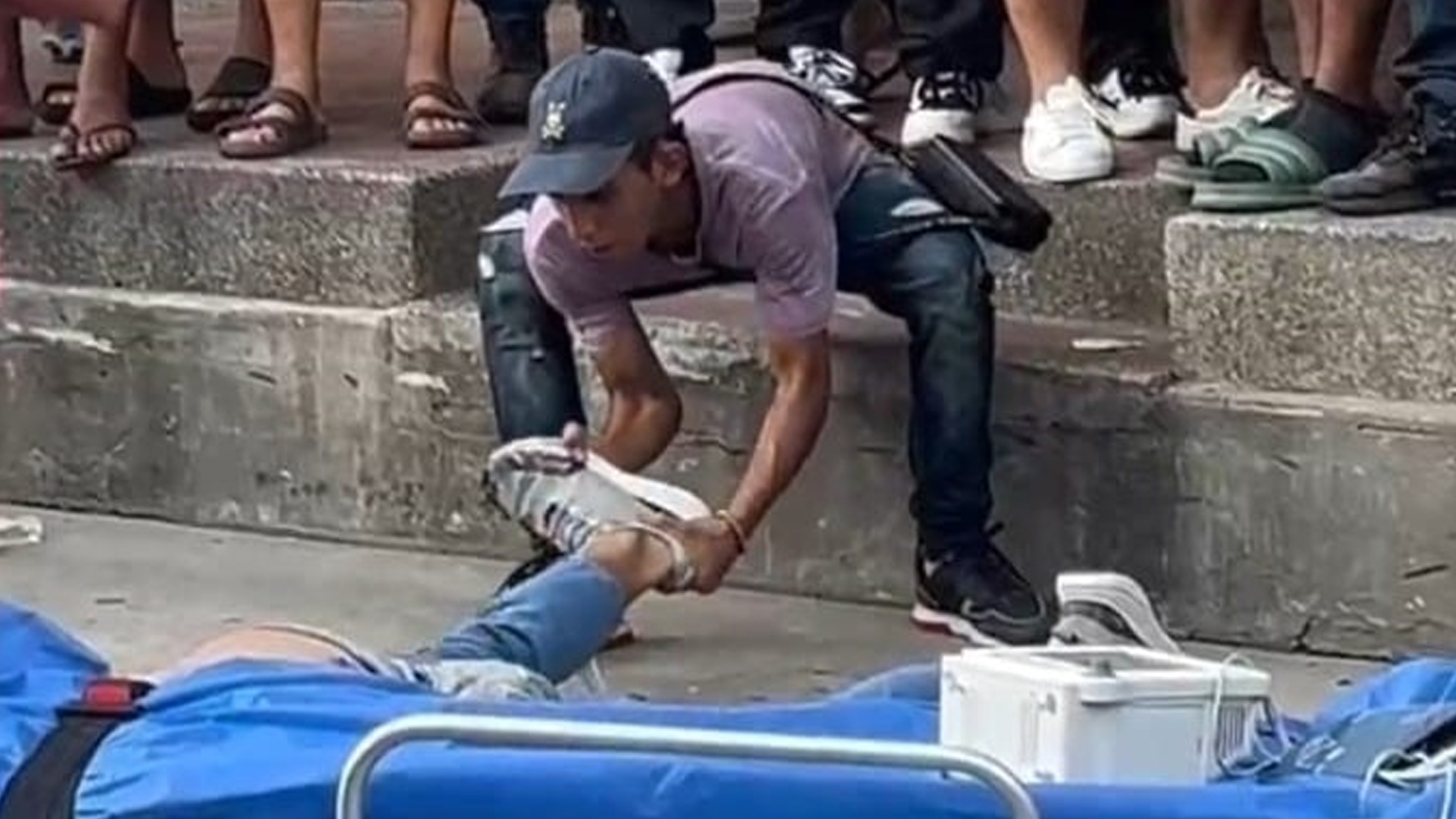 Momento en que un transeúnte intenta quitarle uno de los zapatos al joven malherido