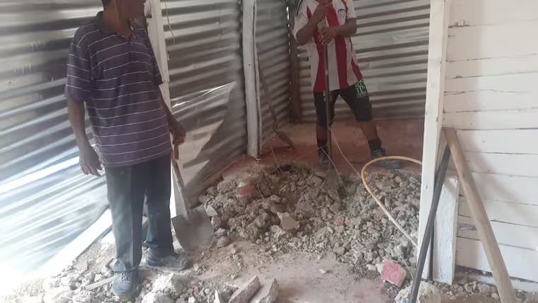 Vecinos rompiendo el piso de la vivienda de Loma Roja.