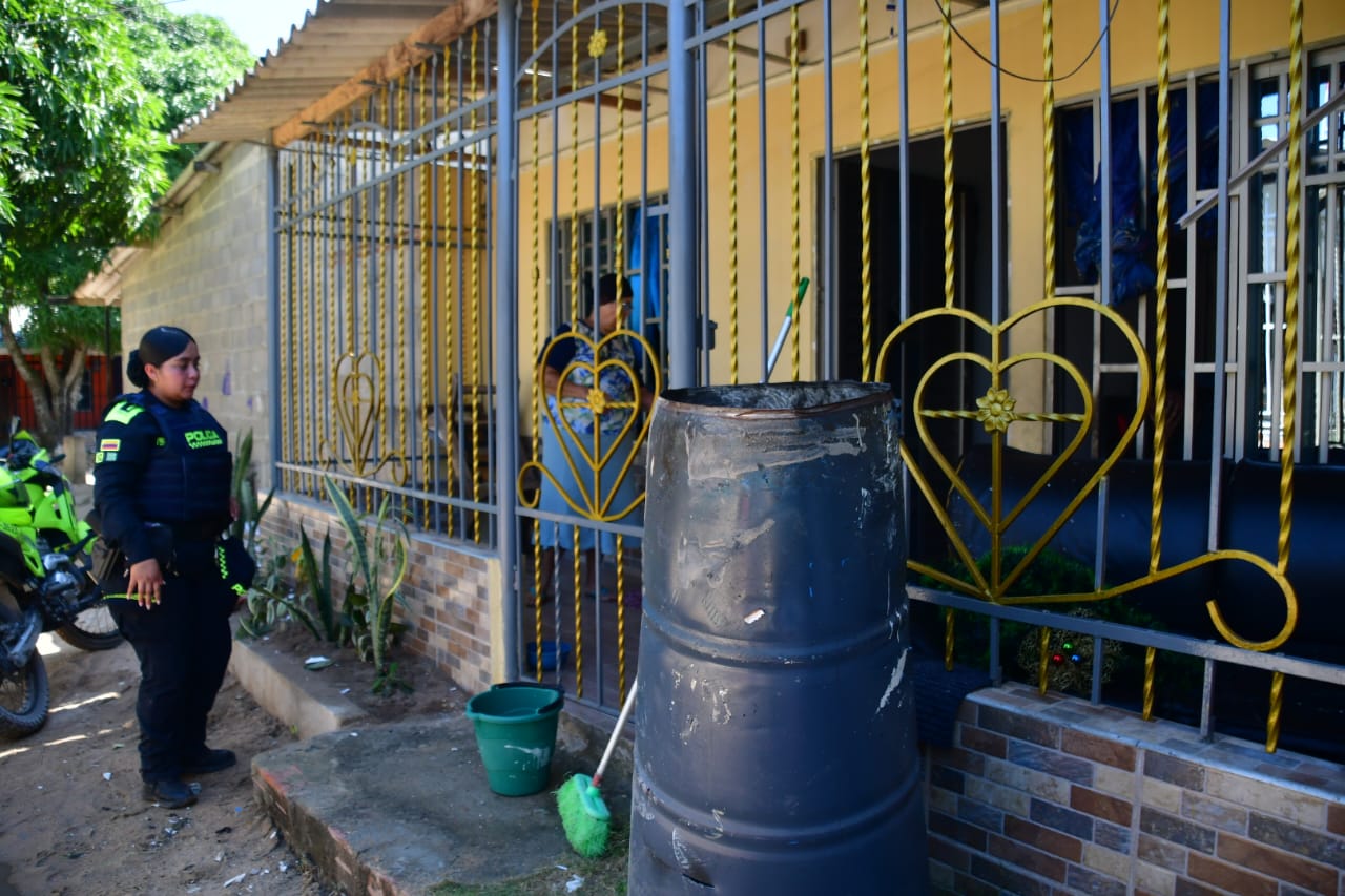 Una policía llega hasta la vivienda donde se presentó la emergencia. Al lado el tambor metálico.