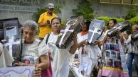 Un grupo de madres buscadoras carga entre sus brazos ataúdes simbólicos con las fotos impresas de sus desaparecidos.
