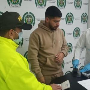 Sebastián Meneses Toro en medio de la toma de huellas tras su captura en Bogotá. 