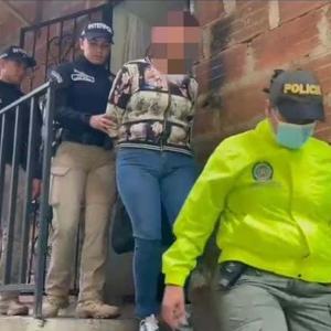 La mujer capturada siendo retirada de su vivienda bajo la compañía de oficiales de la Policía 