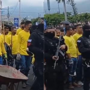 Prisioneros llevados a limpiar las calles mientras son custodiados por la Policía.