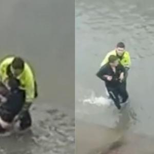 Momento en el que el patrullero auxilia a un ciudadano a salir de un caño. 