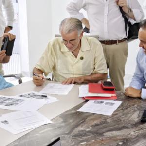 El gobernador Eduardo Verano pone su firma en unos documentos, acompañado por personal de la ANI