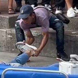 Momento en que un transeúnte intenta quitarle uno de los zapatos al joven malherido