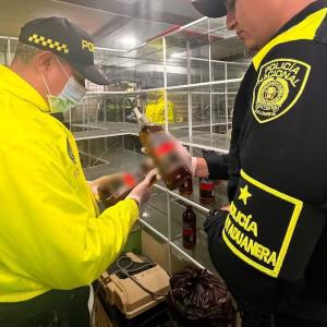 Autoridades decomisando botellas de whisky ilegal.