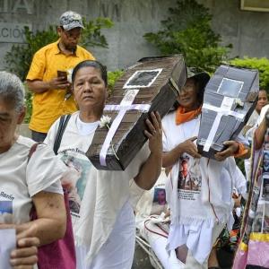 Un grupo de madres buscadoras carga entre sus brazos ataúdes simbólicos con las fotos impresas de sus desaparecidos.
