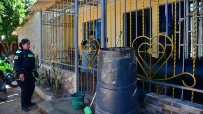 Una policía llega hasta la vivienda donde se presentó la emergencia. Al lado el tambor metálico.