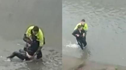 Momento en el que el patrullero auxilia a un ciudadano a salir de un caño. 