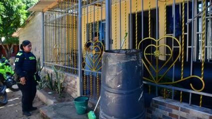 Una policía llega hasta la vivienda donde se presentó la emergencia. Al lado el tambor metálico.