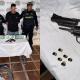 Fotografía de uno de los capturados junto con un arma incautada.